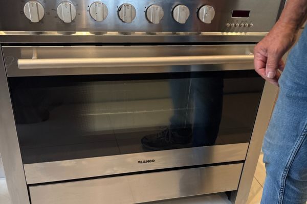 Technician inspecting a stainless steel oven during an oven repair in Melbourne