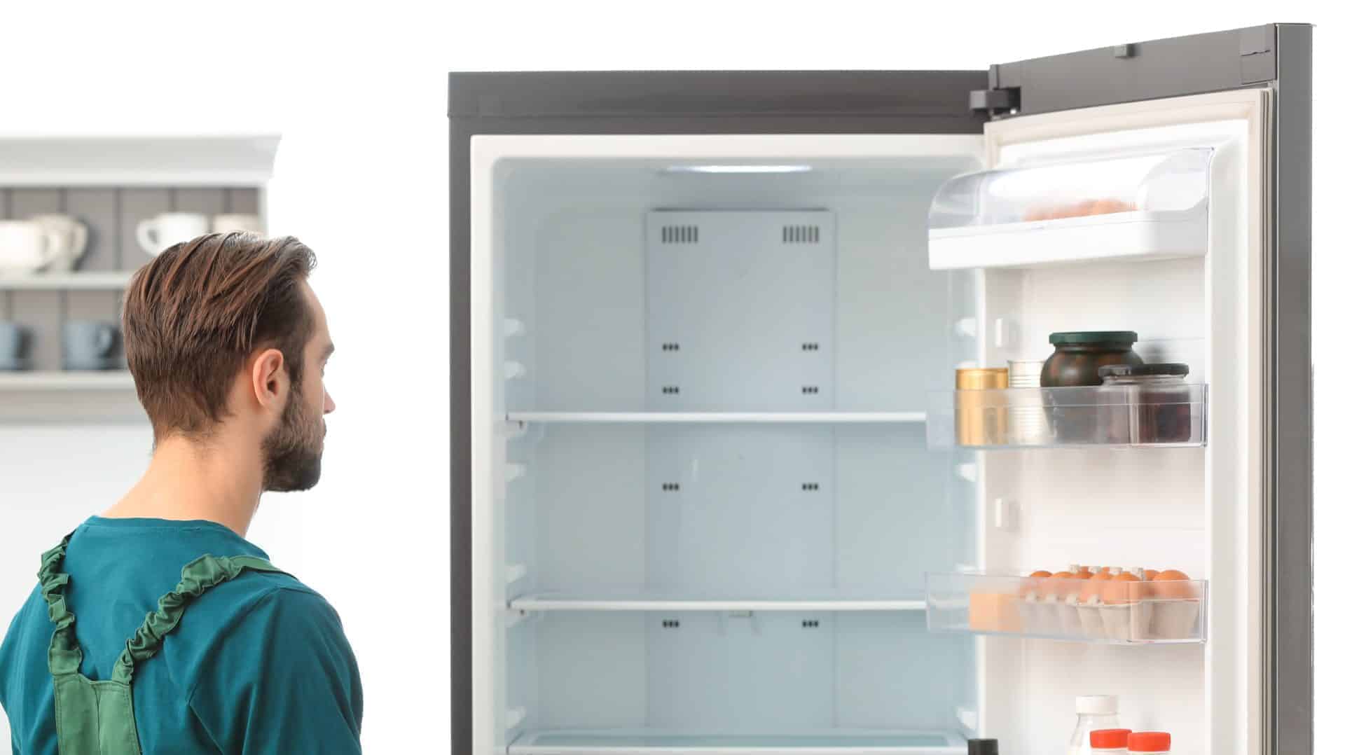 Melbourne Freezer Repairs. Repairman wearing jumpsuit looking and checking into freezer to repair it.