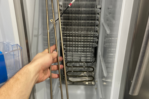 Technician inspecting freezer evaporator coils during freezer repair in Melbourne